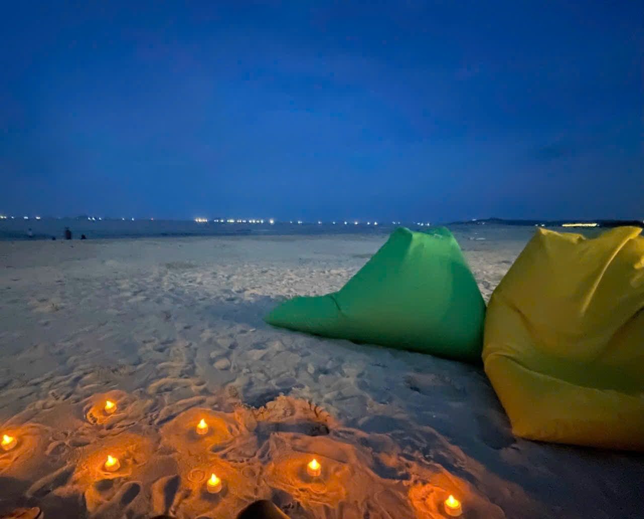 Bean bags and candles on the sand at night
