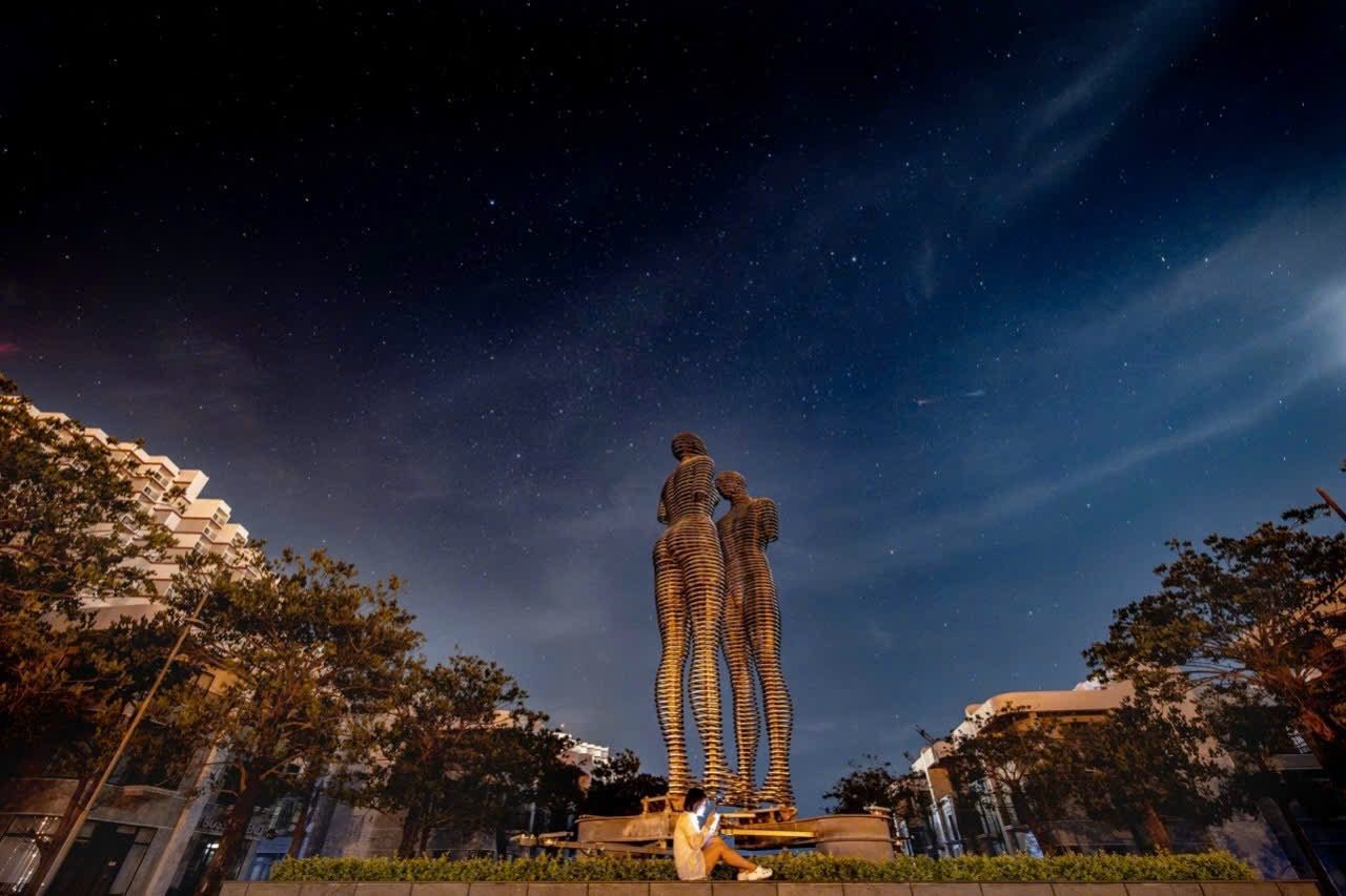 Glowing sculpture of two figures under a starry sky